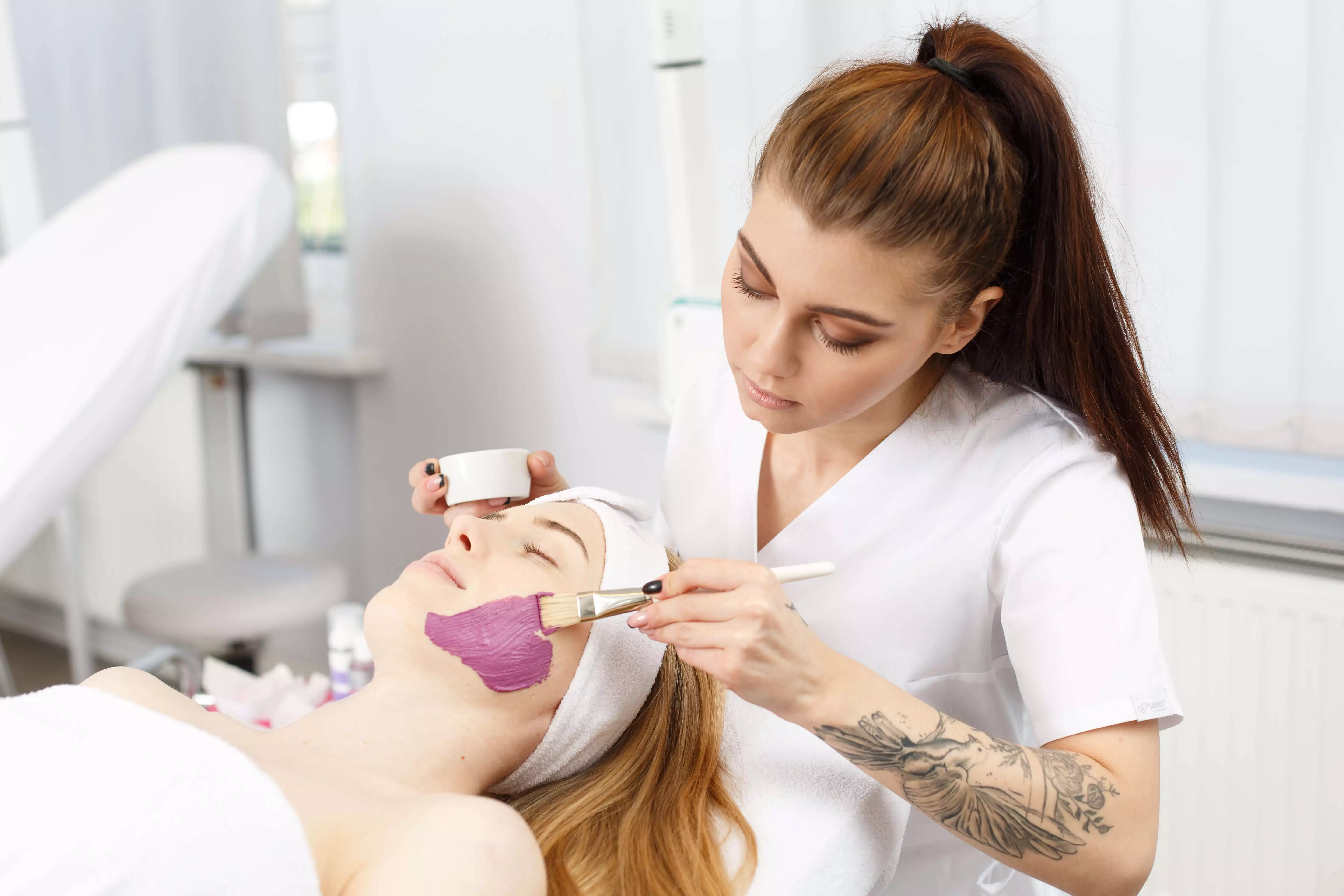 Studentka nakłada glinkę na modelkę w trakcie zajęć w pracowni kosmetycznej na studiach I stopnia